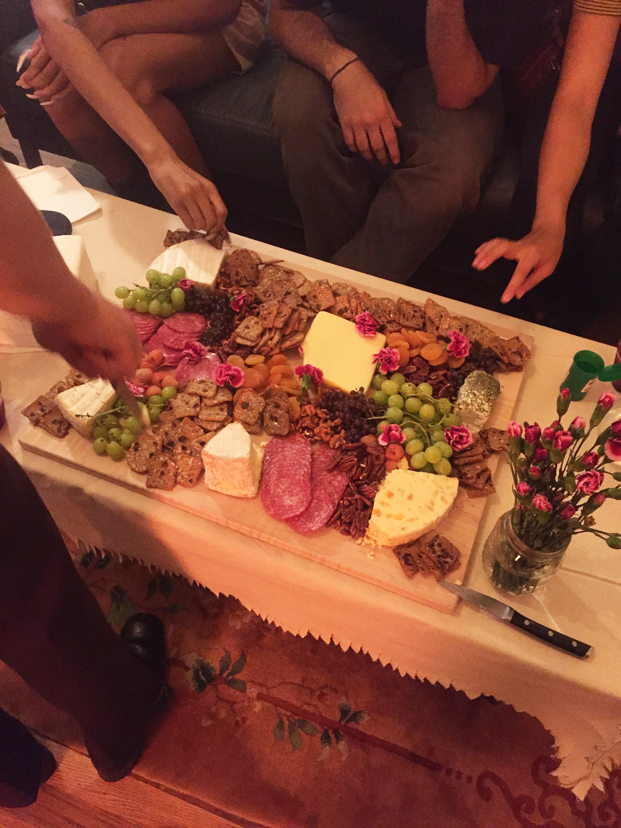 Hands reaching for a charcuterie board on a low coffee table